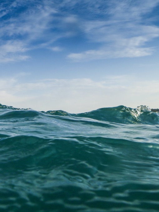blue green ocean against blue sky with clouds